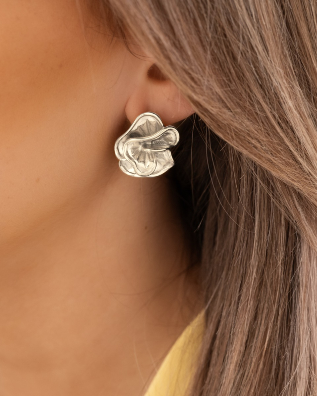 Model draagt zilveren bloemen studs