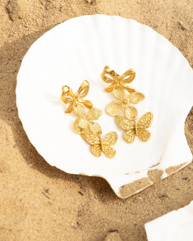 gouden statement oorbellen op het strand op witte schelp