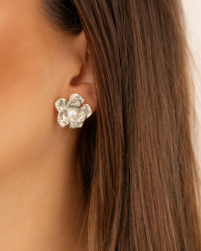 Model draagt zilveren bloemetjes studs met pareltje