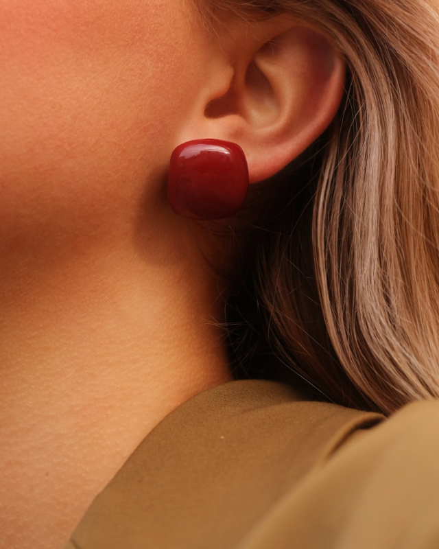 Model draagt rode stud oorbellen