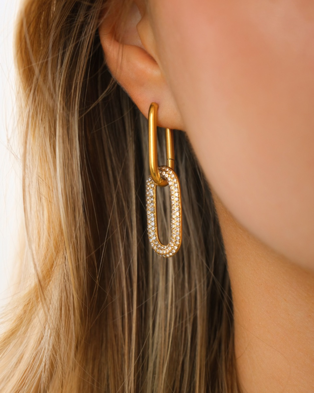 Model draagt gouden dubbele oorringen met steentjes