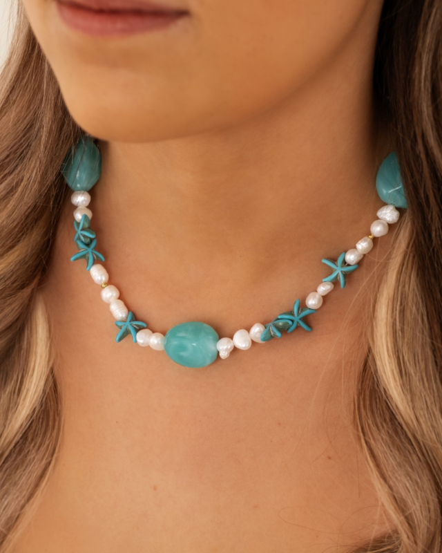 Model draagt parelketting met aqua bedels