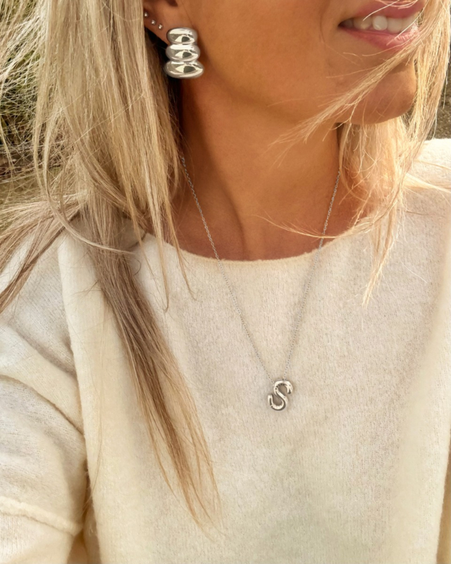 Model draagt zilveren letter ketting