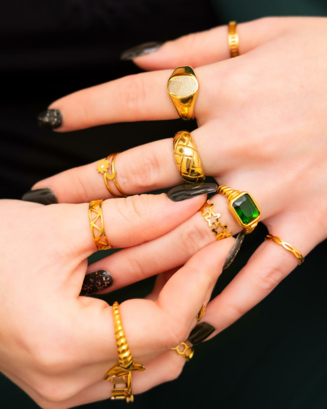 mix van gouden ringen met gravering en groene details om vingers