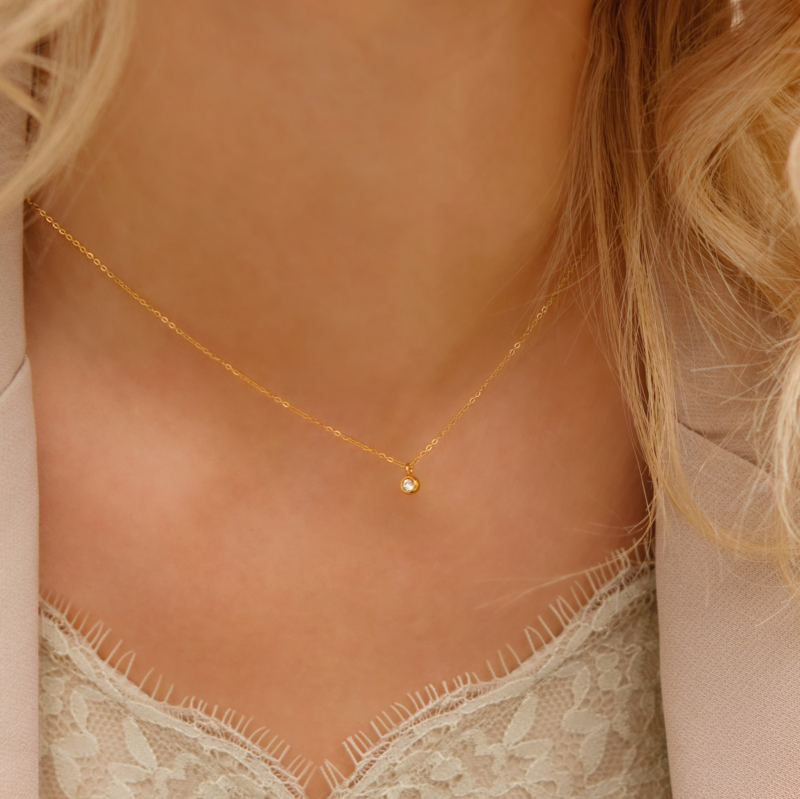 Model draagt gouden ketting met steentje