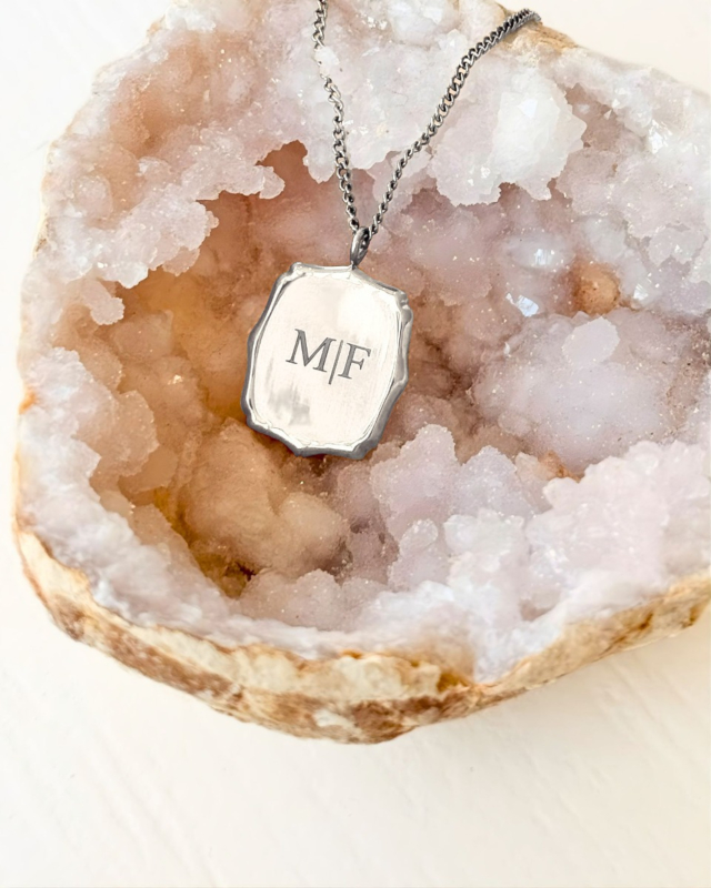 zilveren atelier ketting met initialen op stenen ondergrond