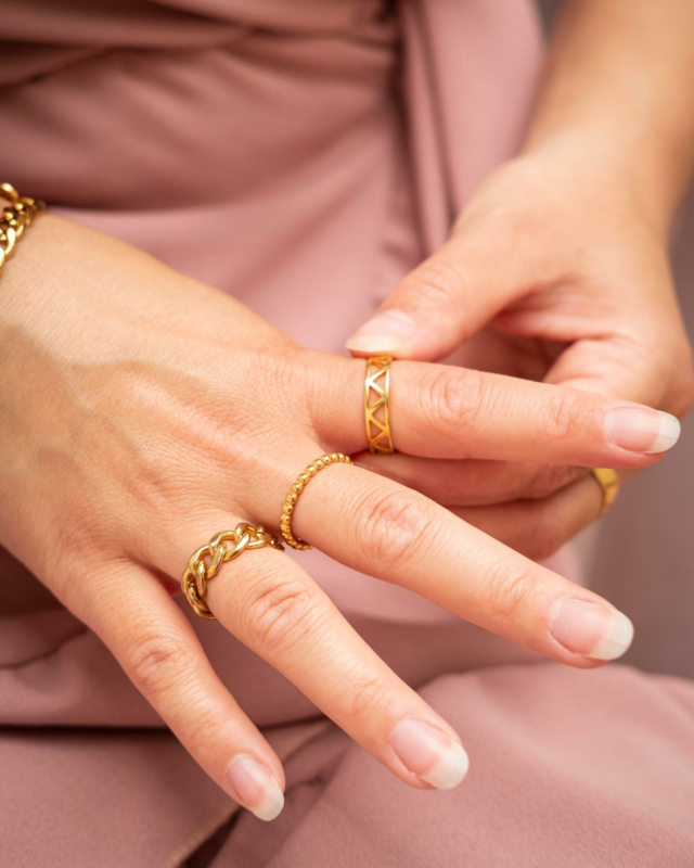 gouden ringen om vingers van vrouw met roze jurk