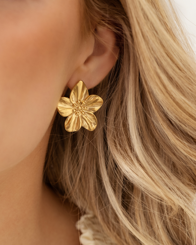 Gouden bloem oorbellen in oor