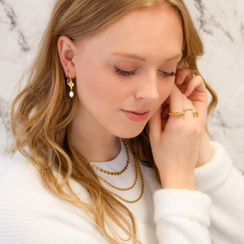 Vrouw met ear cuff in het oor samen met leuke kettingen