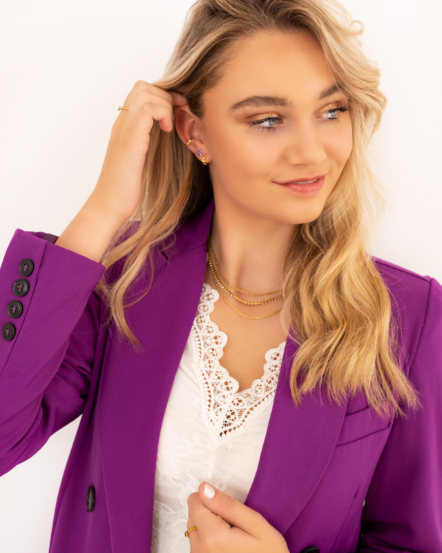 Model draagt oorknopjes purple stone goudkleurig