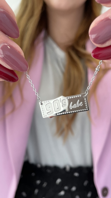 Zilverkleurige ketting met 90's babe in de handen van het model