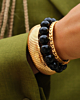 Gouden armparty met bangles en zwarte kralen