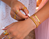 Model draagt gouden armbanden en ringen