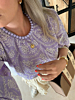 model draagt paarse top met paarse ketting en bloementjes ketting
