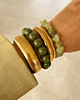 Gouden armparty met bangles en groene kralen