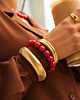 Gouden armparty met bangles en rode kralen