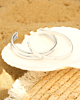 zilveren bangles op schelp op het strand