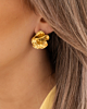 Model draagt gouden bloemen studs