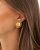 Model draagt gouden studs met zon