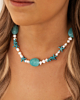 Model draagt parelketting met aqua bedels