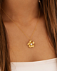 Model draagt gouden bloem ketting met pareltje