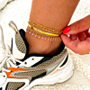Vrouw draagt gouden enkelbandjes met sneaker
