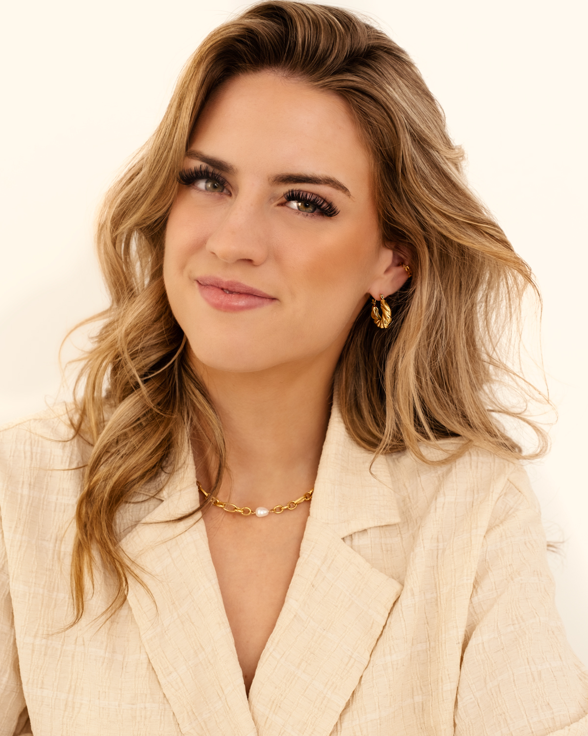 Model draagt gouden sieraden met parel en hoops