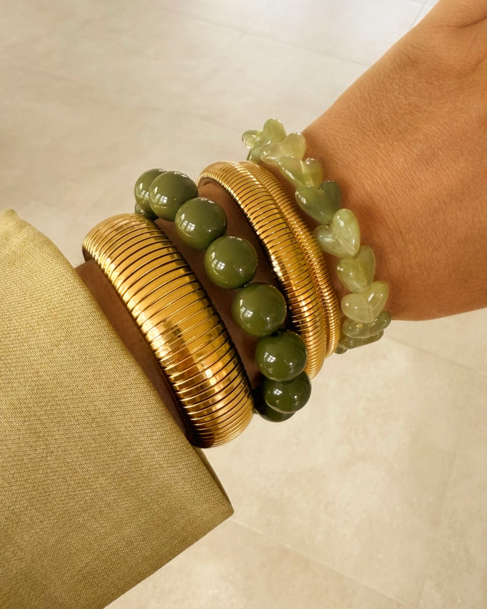 Gouden armparty met bangles en groene kralen