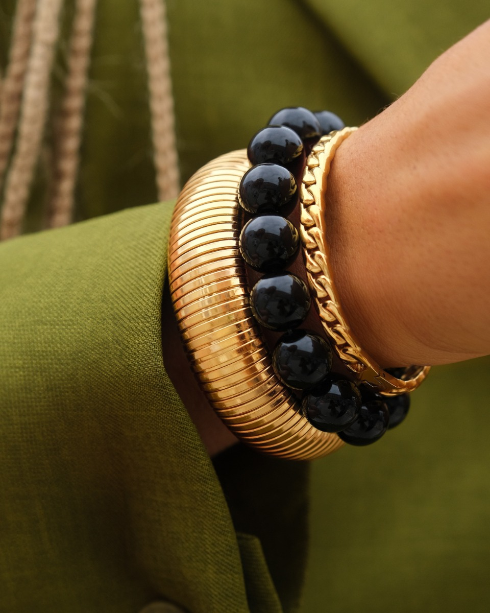 Gouden armparty met bangles en zwarte kralen