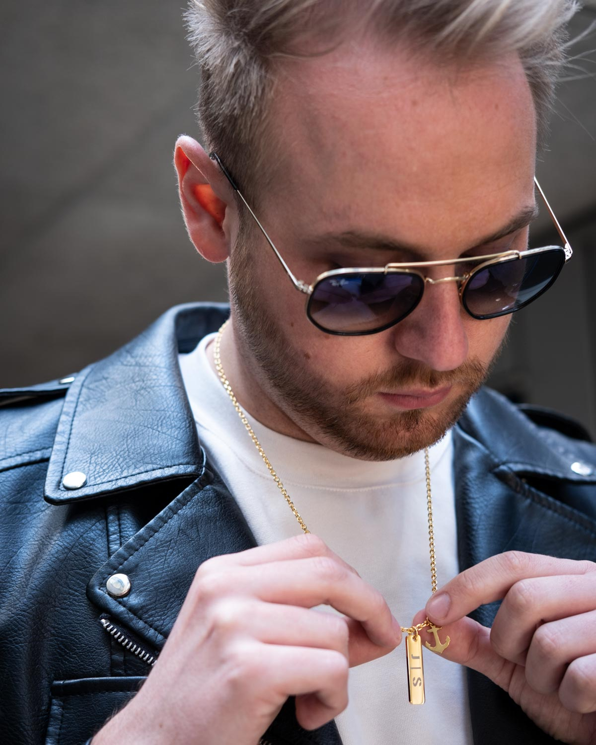 man draagt gouden ketting met ankertje om hals