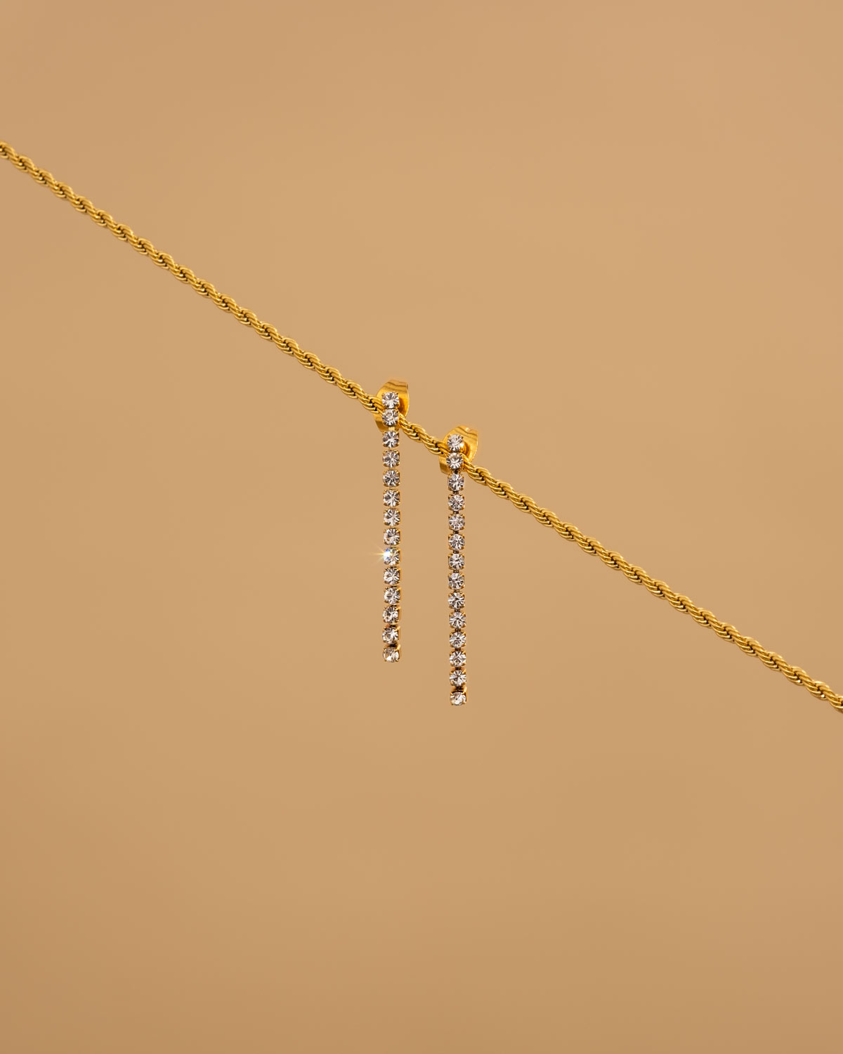 shiny tennis earrings op beige achtergrond