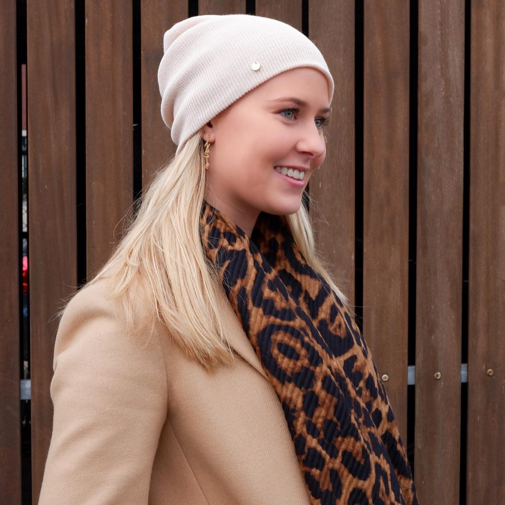 Meisje met blond haar en leopard sjaal en muts