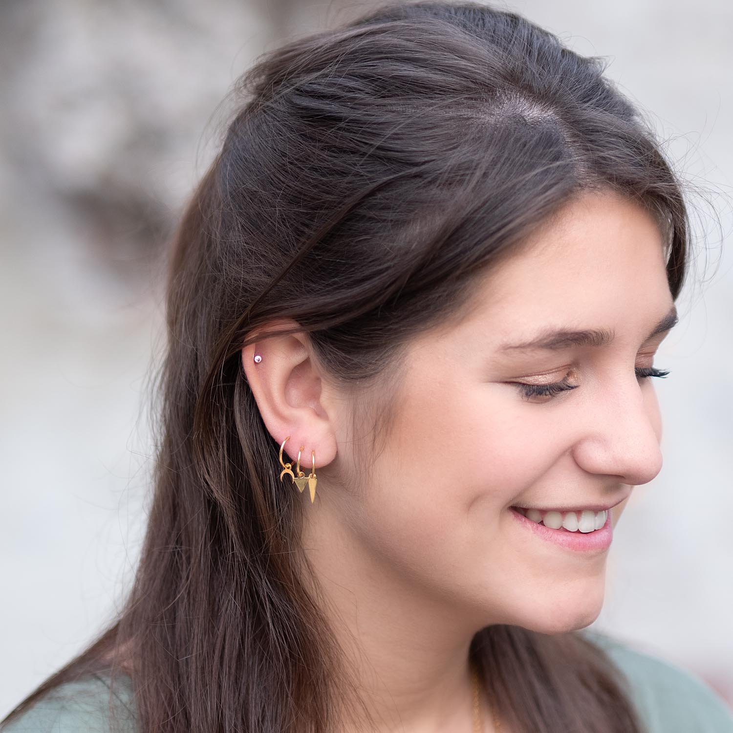 meisje met bruine haren en groene jurk en gouden oorbellen