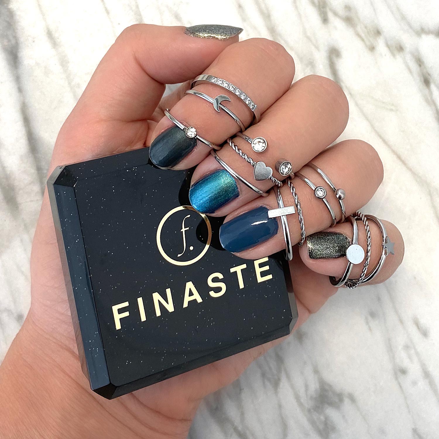 Zilveren ringen bij hand met blauwe nagellak en finaste sieradendoosje