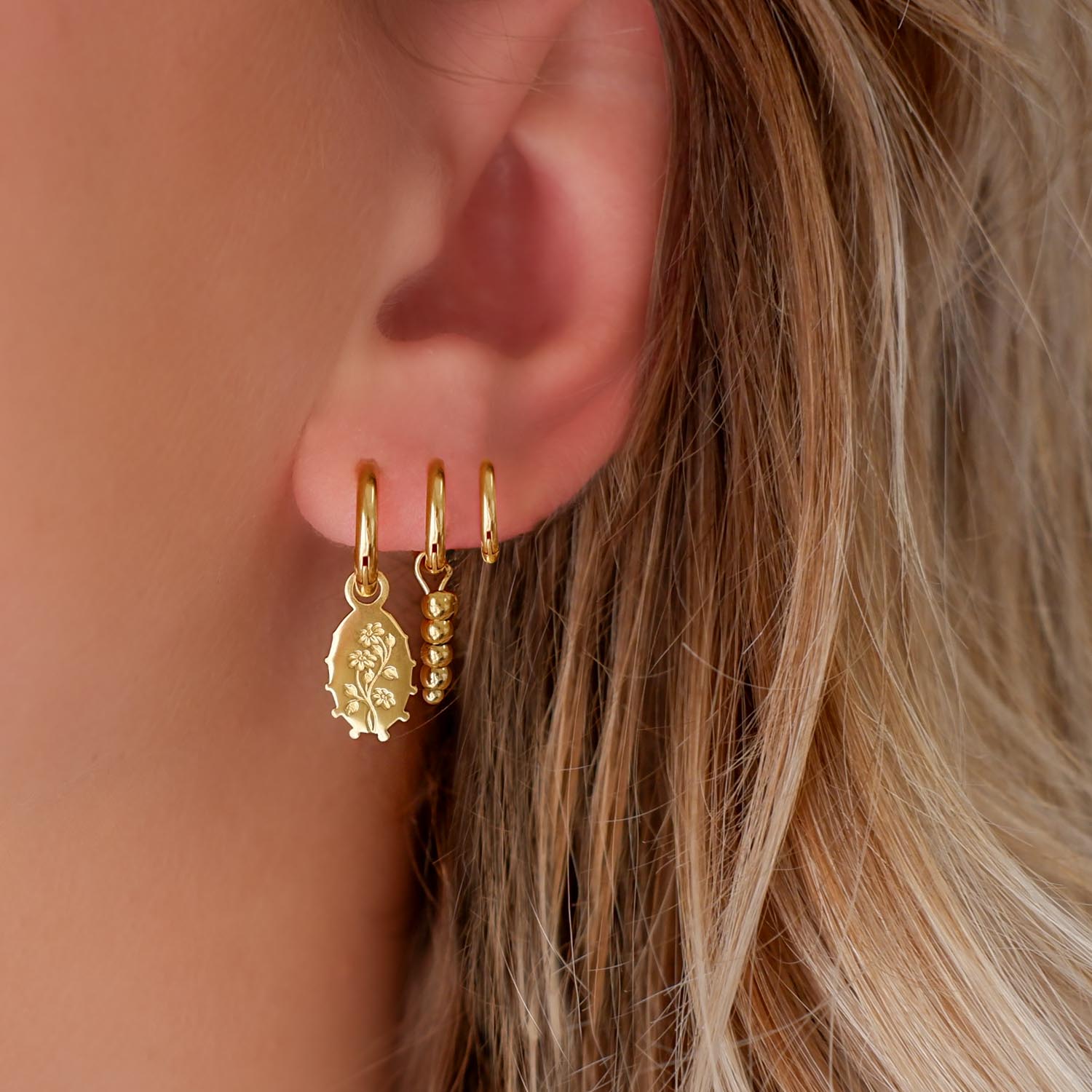 blonde vrouw draagt gouden hanger oorbellen