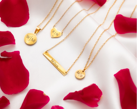 4 gouden kettingen initials. Achtergrond valentijn rozenblaadjes.