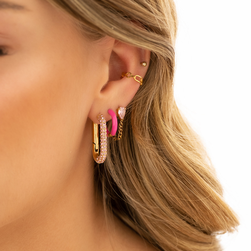 Gouden earparty met roze details. De eerste oorbel is een ovale hoop met aan de voorkant roze steentjes, de 2e is een kleinere hoop in het knal roze en als 3e een ketting oorbel ben roze steentje aan de bovenkant