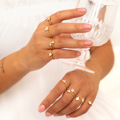 Model draagt 12 gouden ringen om handen. De ringen hebben allemaal een steentje met een ander vormpje